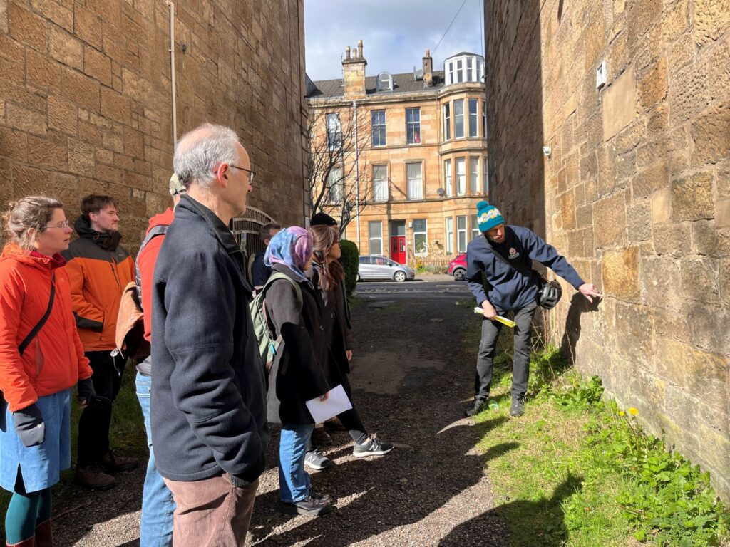 Group of people outside a traditional sandstone tenement learning about home retrofit.