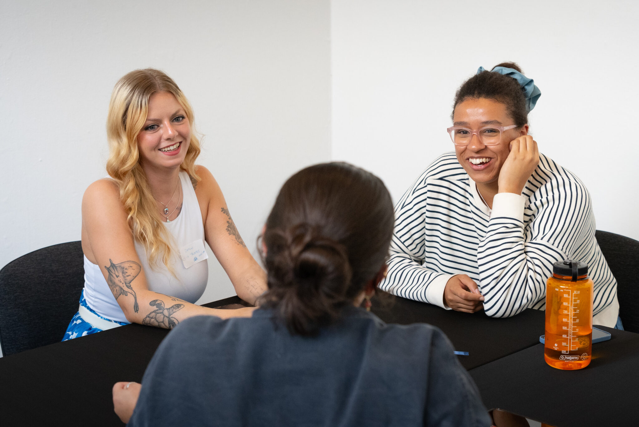 Three people sat at table laughing